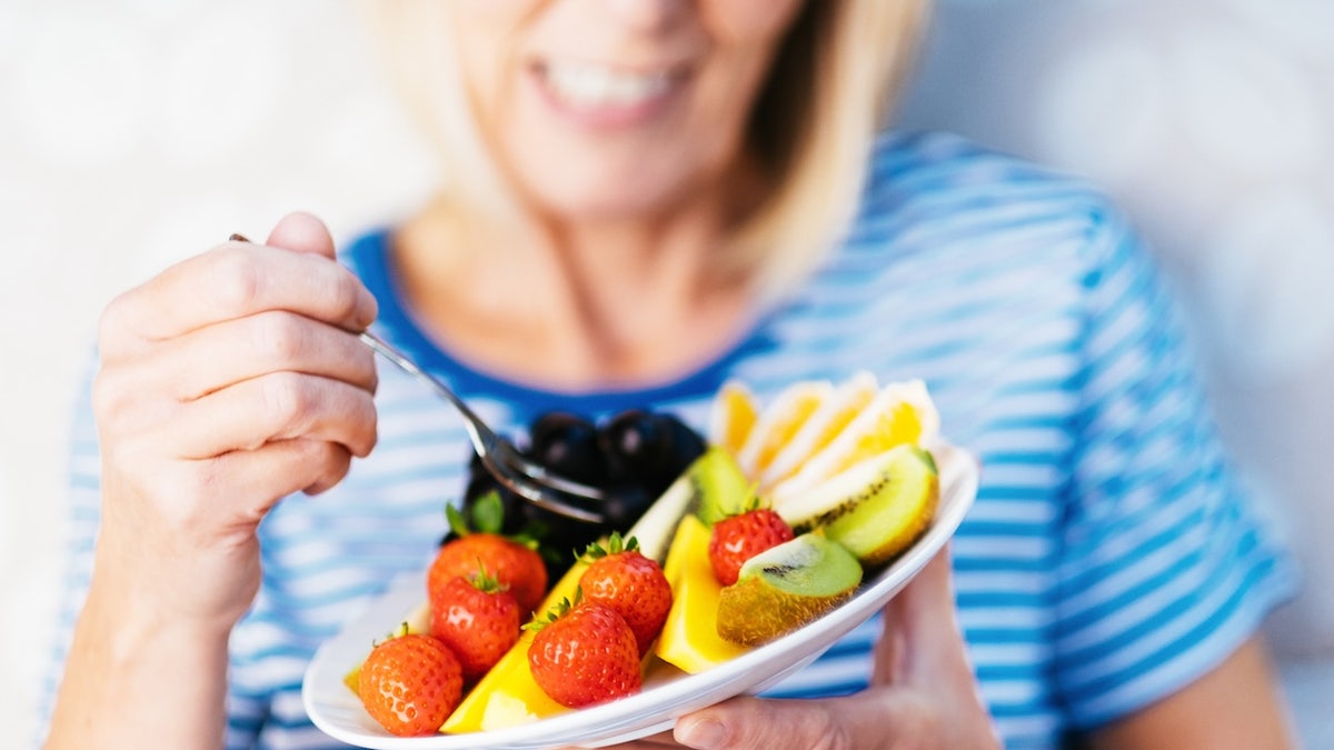 Older woman eating fruit