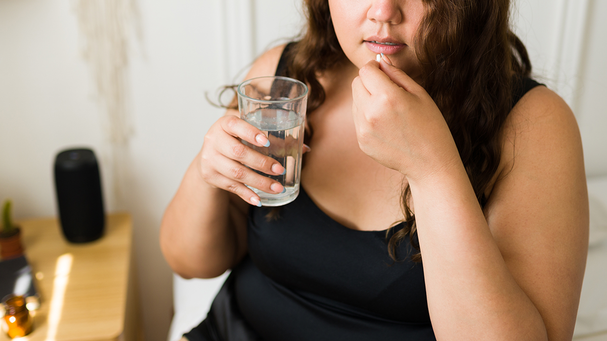 woman takes pill with water