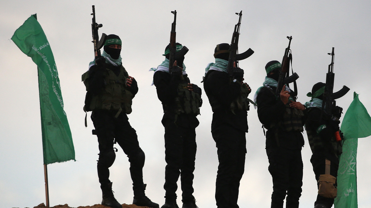 Hamas terrorists in black with green flags, weapons
