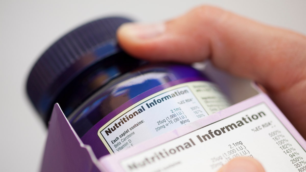 person reads vitamin nutrition label