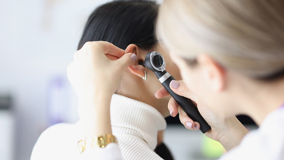 Doctor performing ear exam on a woman