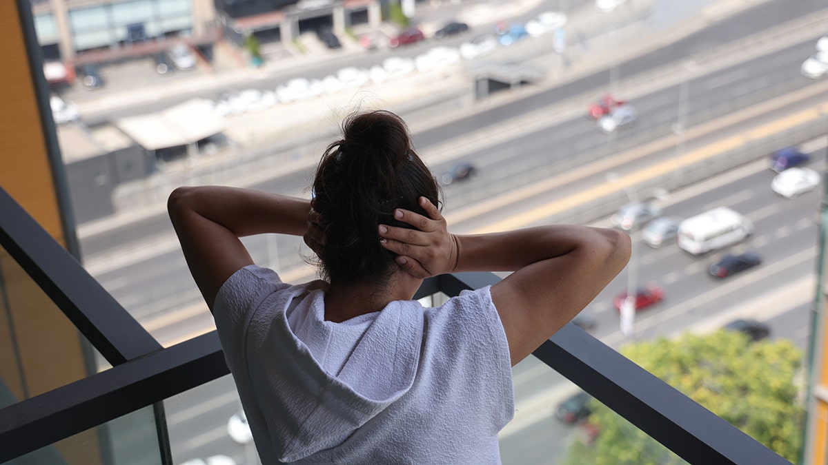 Loud noises of the city, woman covers ear on balcony