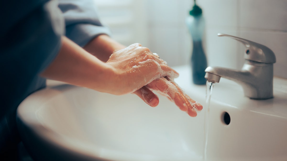 Person washing their hands in a sink.
