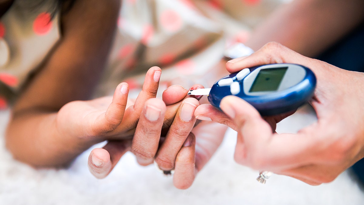 Mother checks kid's diabetes by monitoring blood glucose