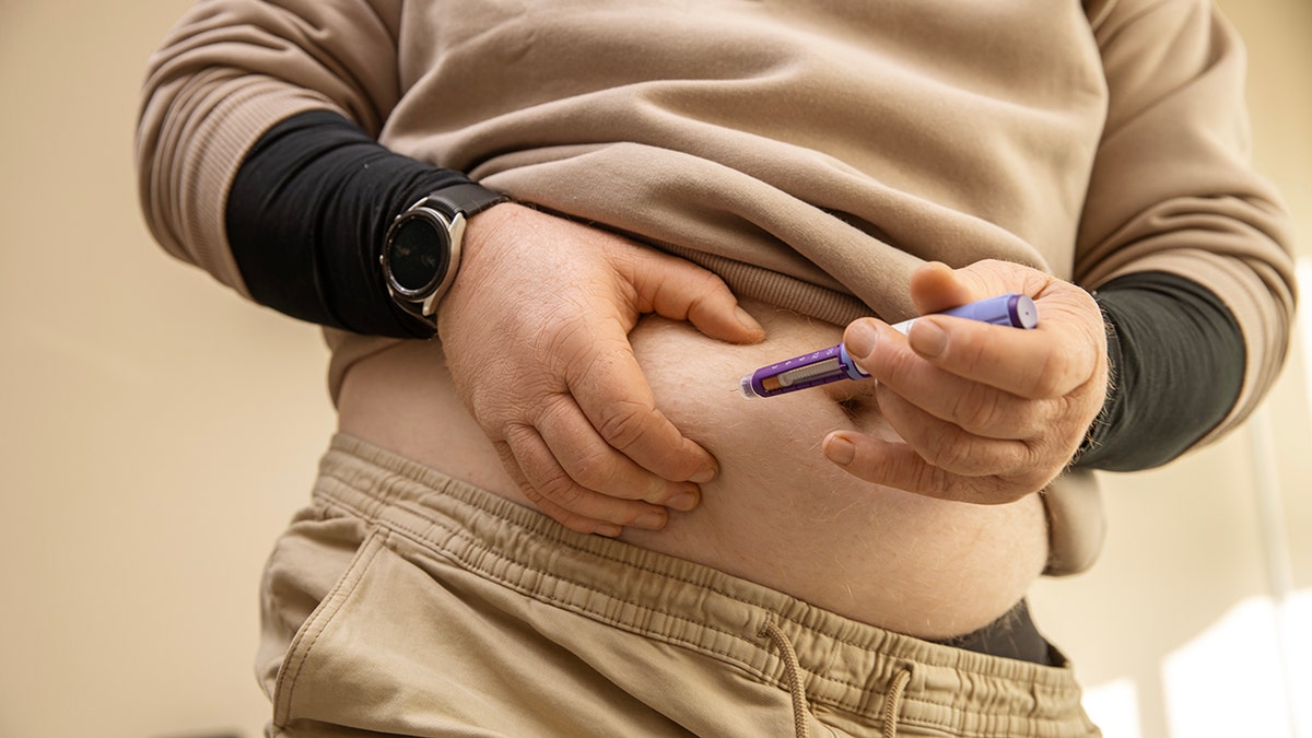 Man gives himself semaglutide injection in his belly. No face is shown, just the torso.