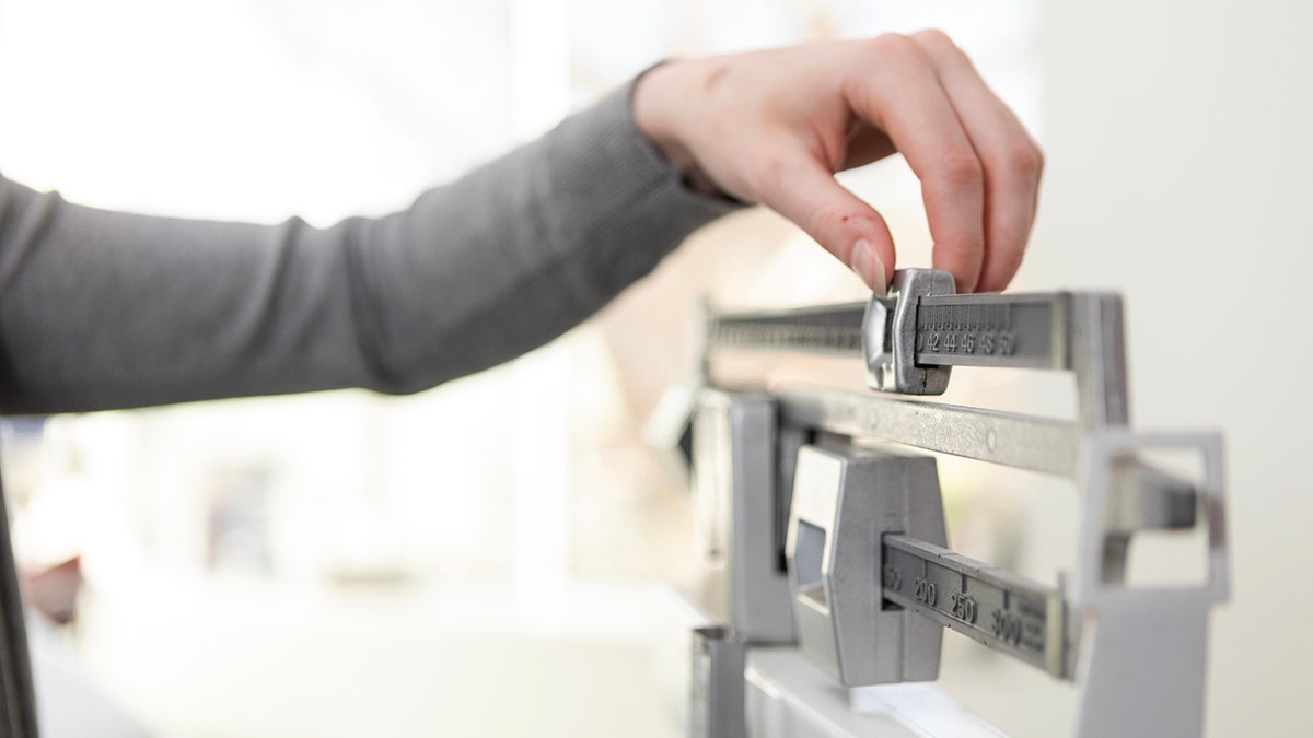 hand adjusts the scale at a doctor's office to determine weight