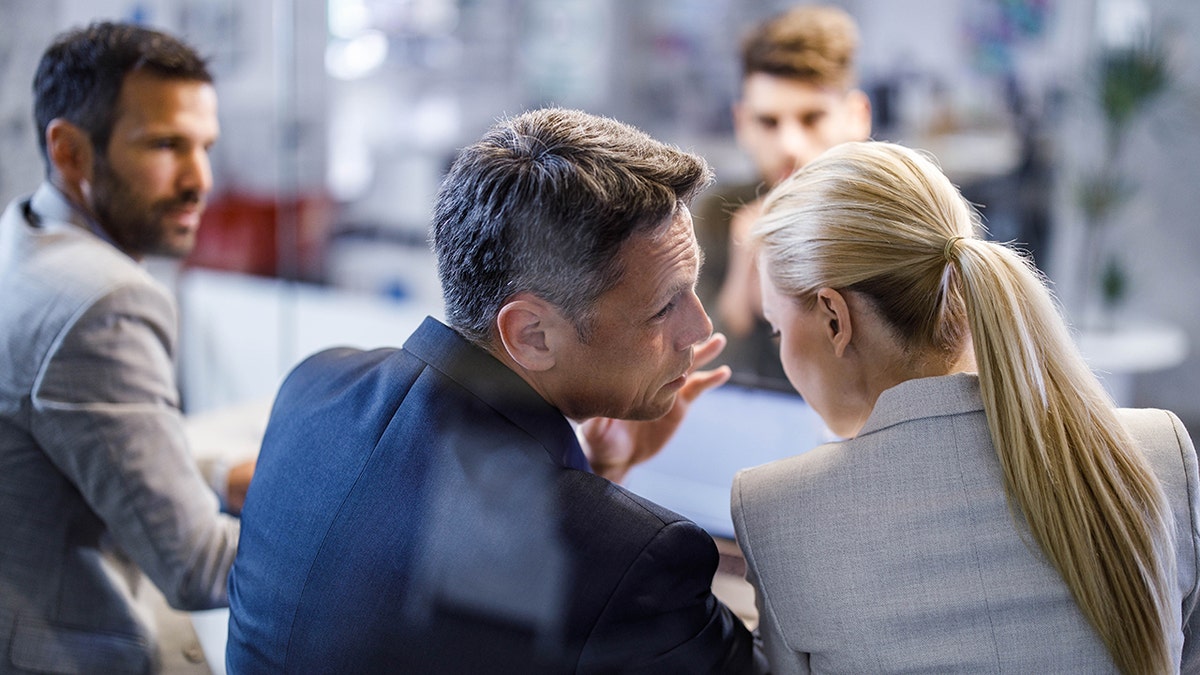 coworkers whisper and gossip during a business meeting