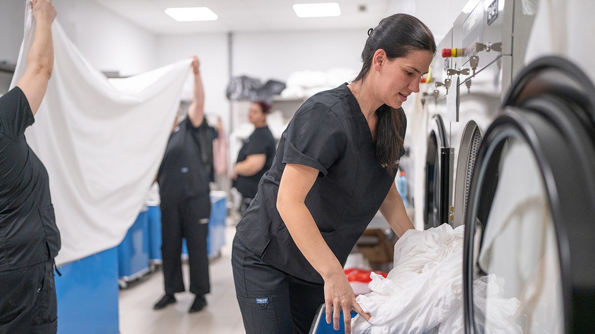 Woman washes clothes at an industrial washer