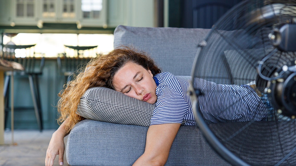 woman lying in front of fan on couch sleeping