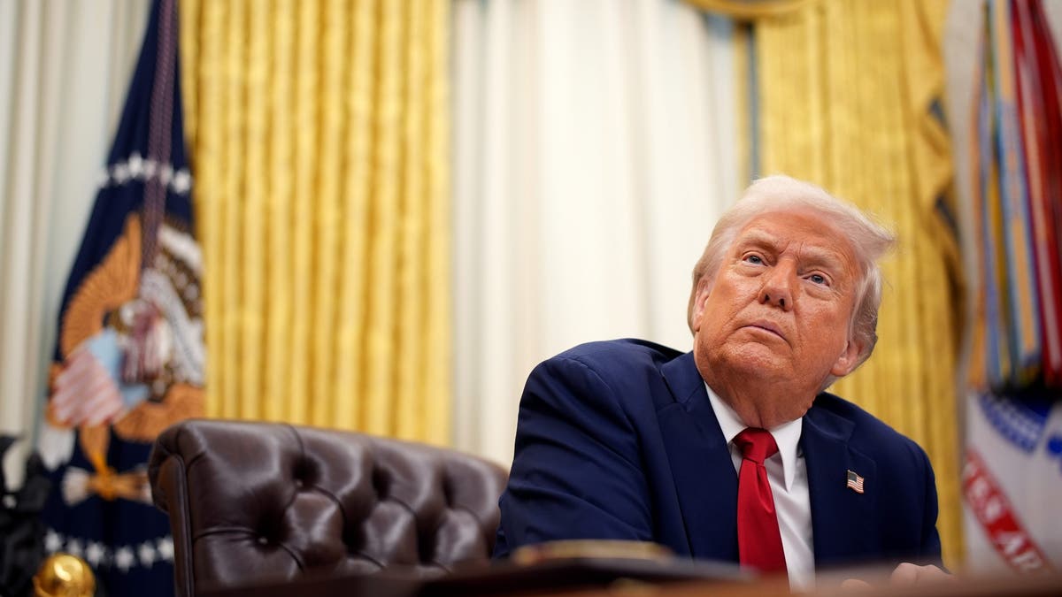 Trump at desk in Oval Office, photo looking up from floor perspective