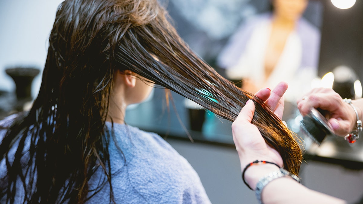 hairdresser brushing client's hair in salon