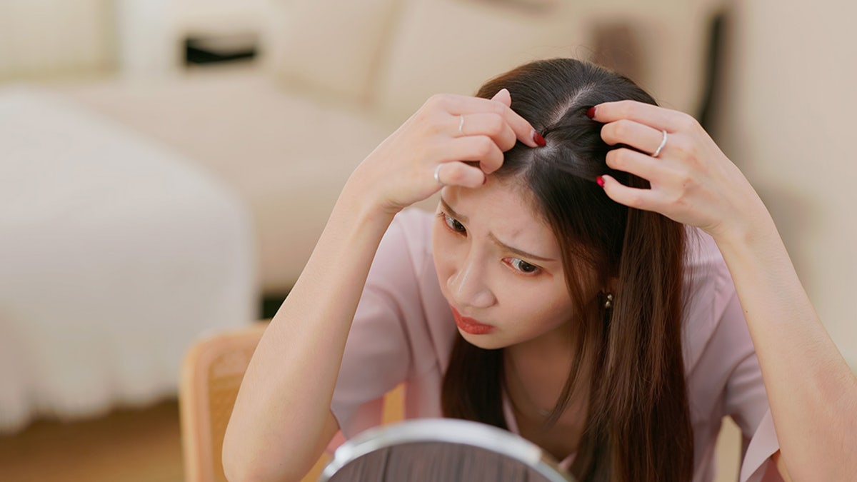 woman examining hair loss