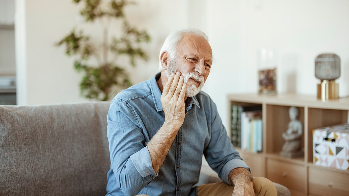 Man holding his face in pain, seemingly because of a toothache.