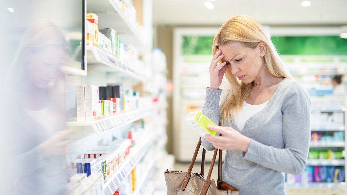 Woman with headache perusing pharmacy.