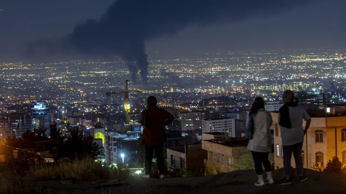 People gather on a hill to watch smoke rising in the distance from an Israeli airstrike in Tehran, Iran, on June 14, 2025.&nbsp;