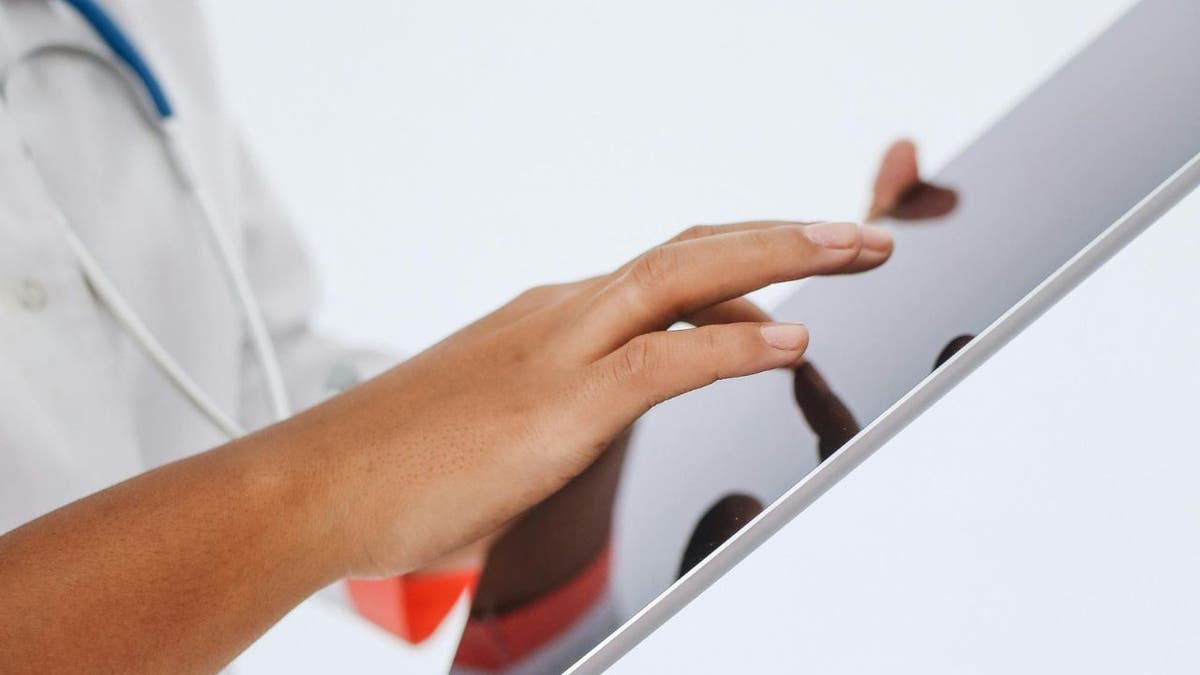 A healthcare professional looking at health data on a tablet.