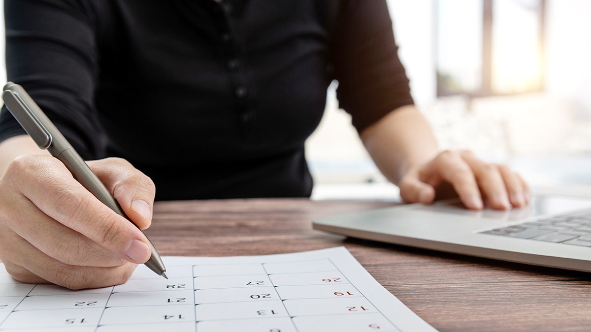 Person marking dates on a calendar