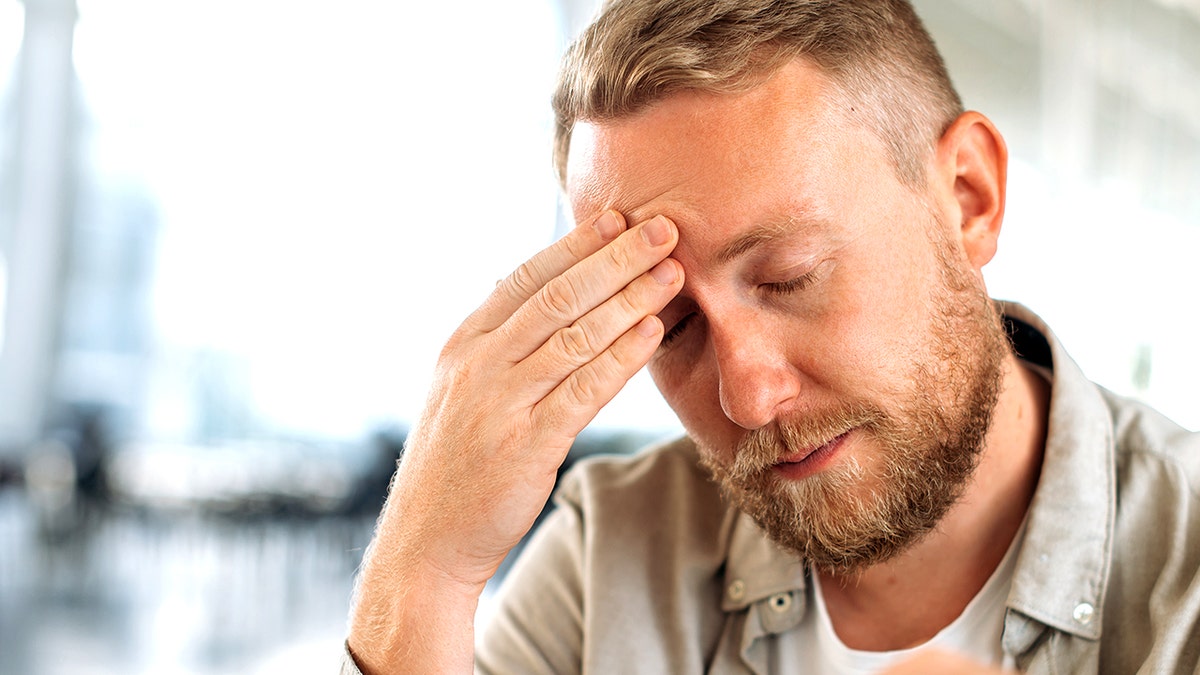 Man holding head while he experiences a migraine