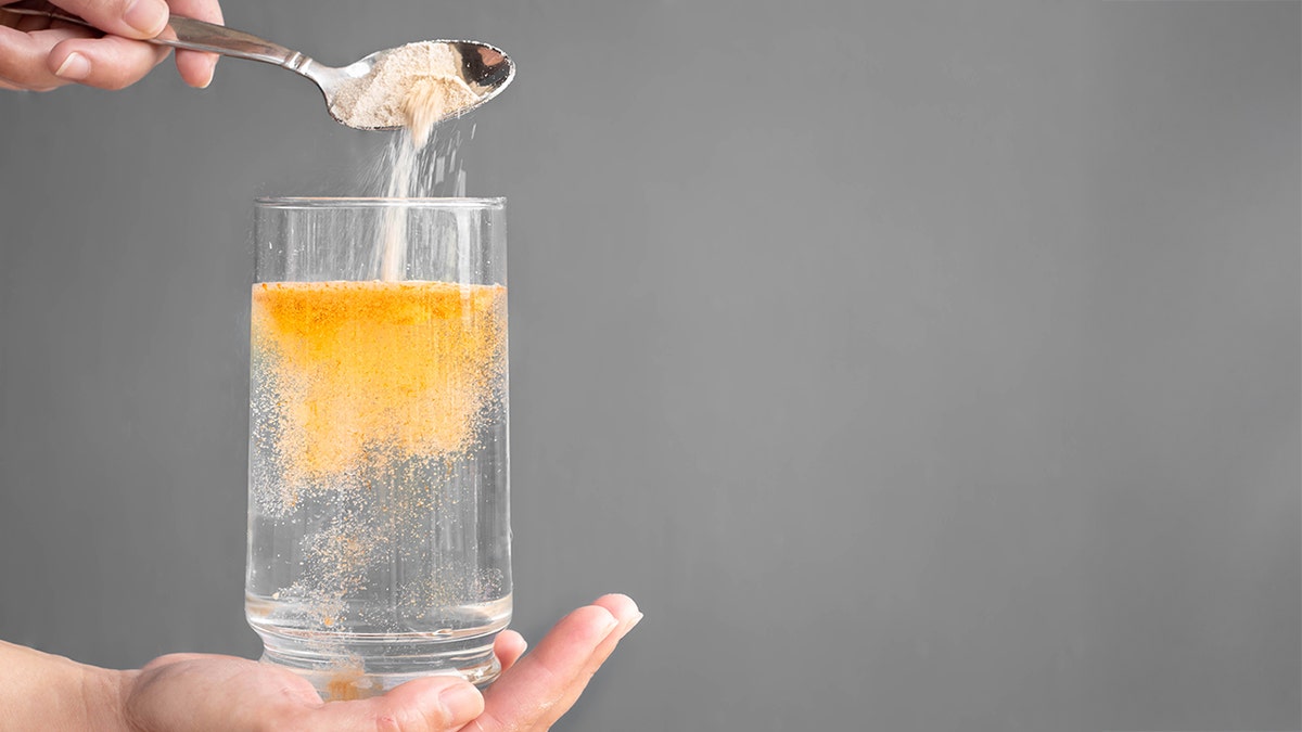 orange powder being mixed in glass of water