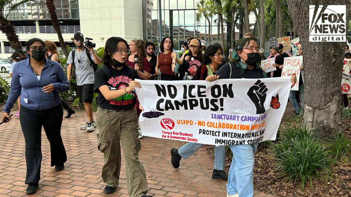Protesters hold a "No ICE on campus!" sign outside Turning Point USA's Student Action Summit.&nbsp;