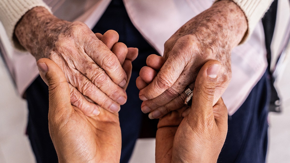 younger person holding hands of older person