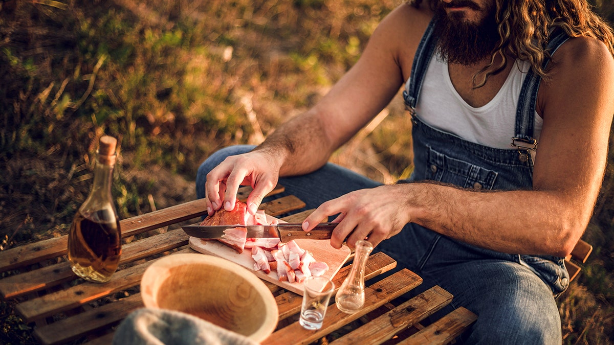 A bearded man eats food outside