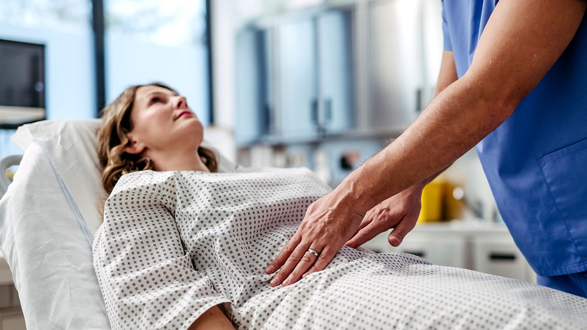 Doctor checking for endometriosis, feeling woman's pelvic area.