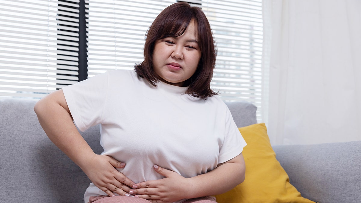 woman grabs her stomach in pain