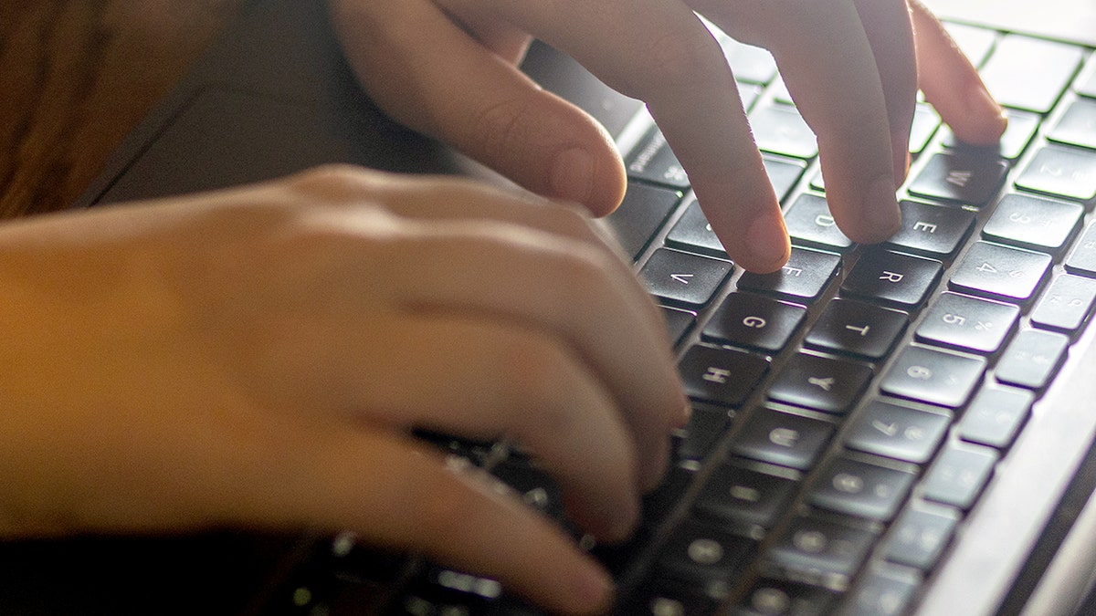 Hands typing on a laptop keyboard.