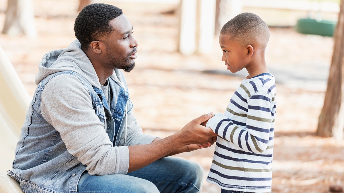 man talking to his son on a playground
