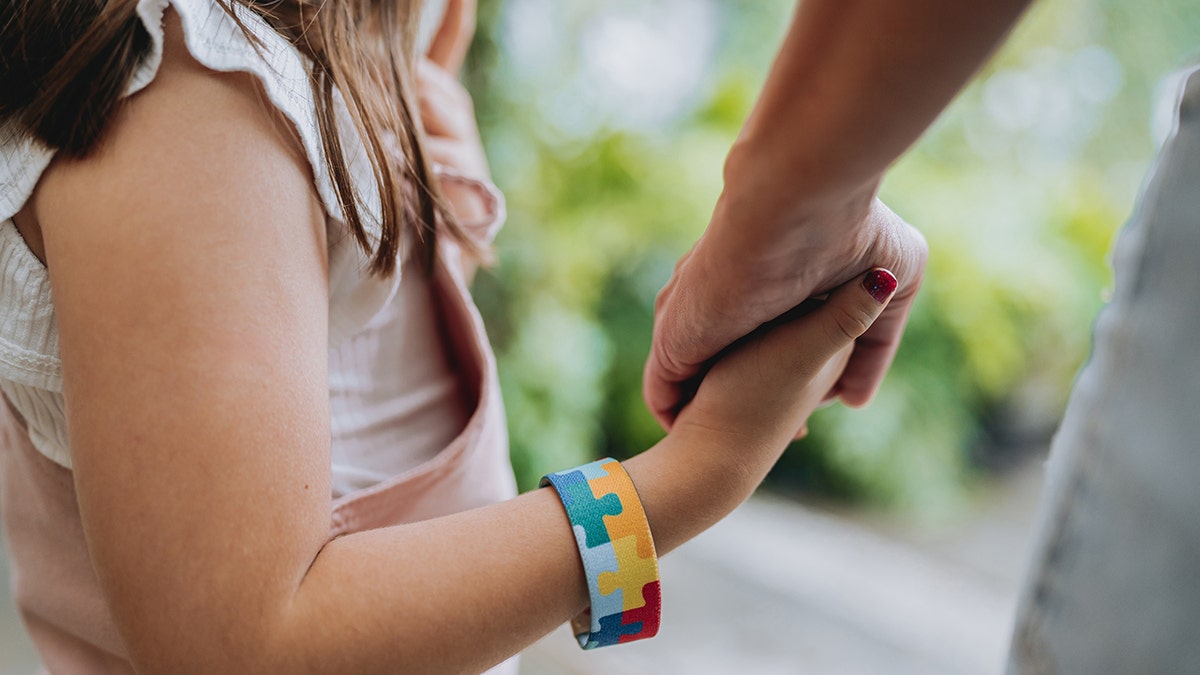 Autistic child holding hands with mother