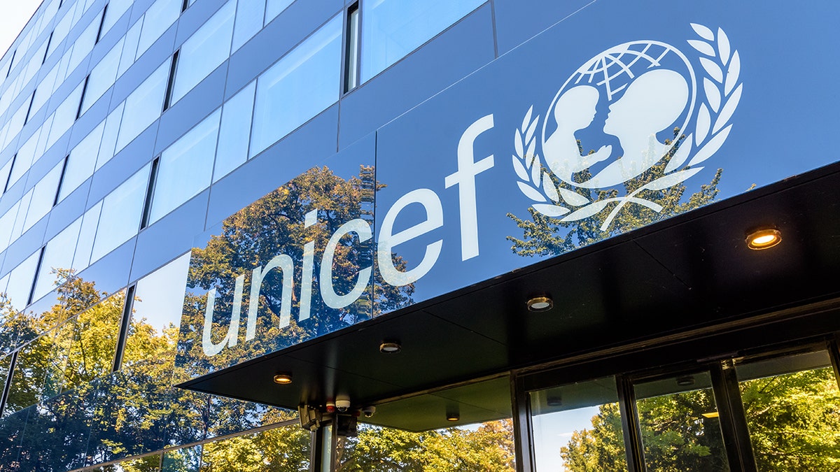 Exterior of headquarters of the Regional Office of the UNICEF in Geneva, Switzerland, logo seen with reflection of trees in building's glass windows.