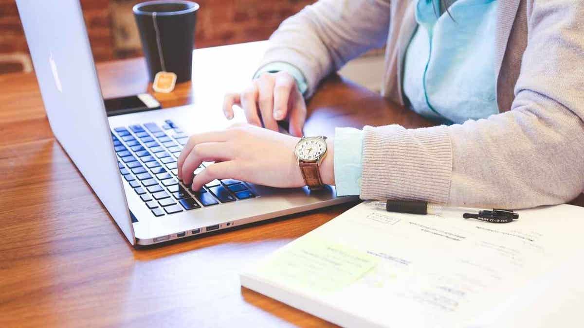 woman types on laptop while sitting at table