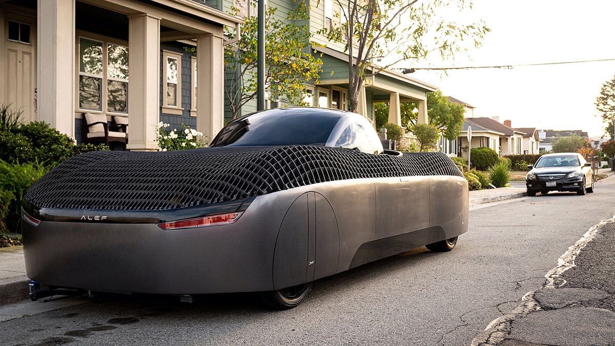 An Alef flying car parked in front of a house