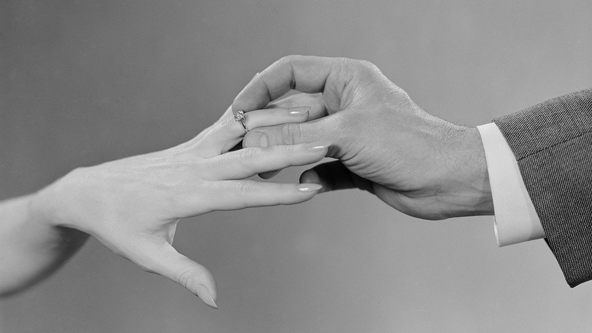 Man slipping an engagement ring on his fiancée.