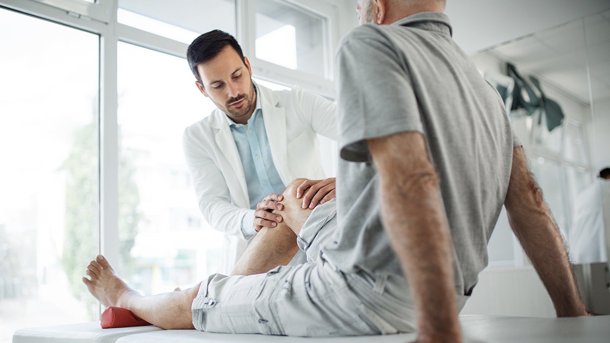 doctor examines a male patient's knee