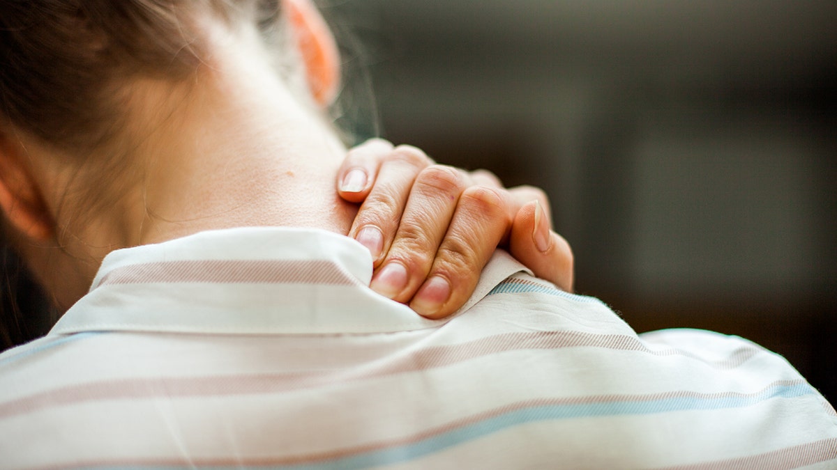 Woman rubbing her neck as though in pain