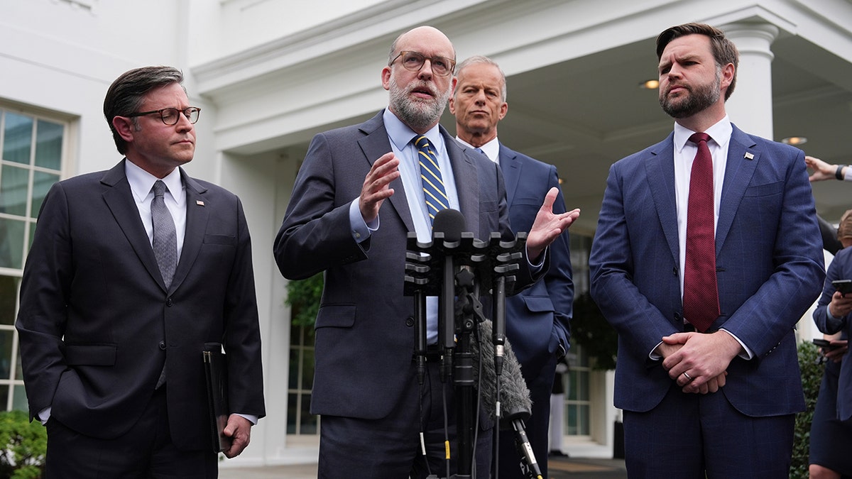 Russell Vought speaking as Mike Johnson, John Thune and JD Vance listen