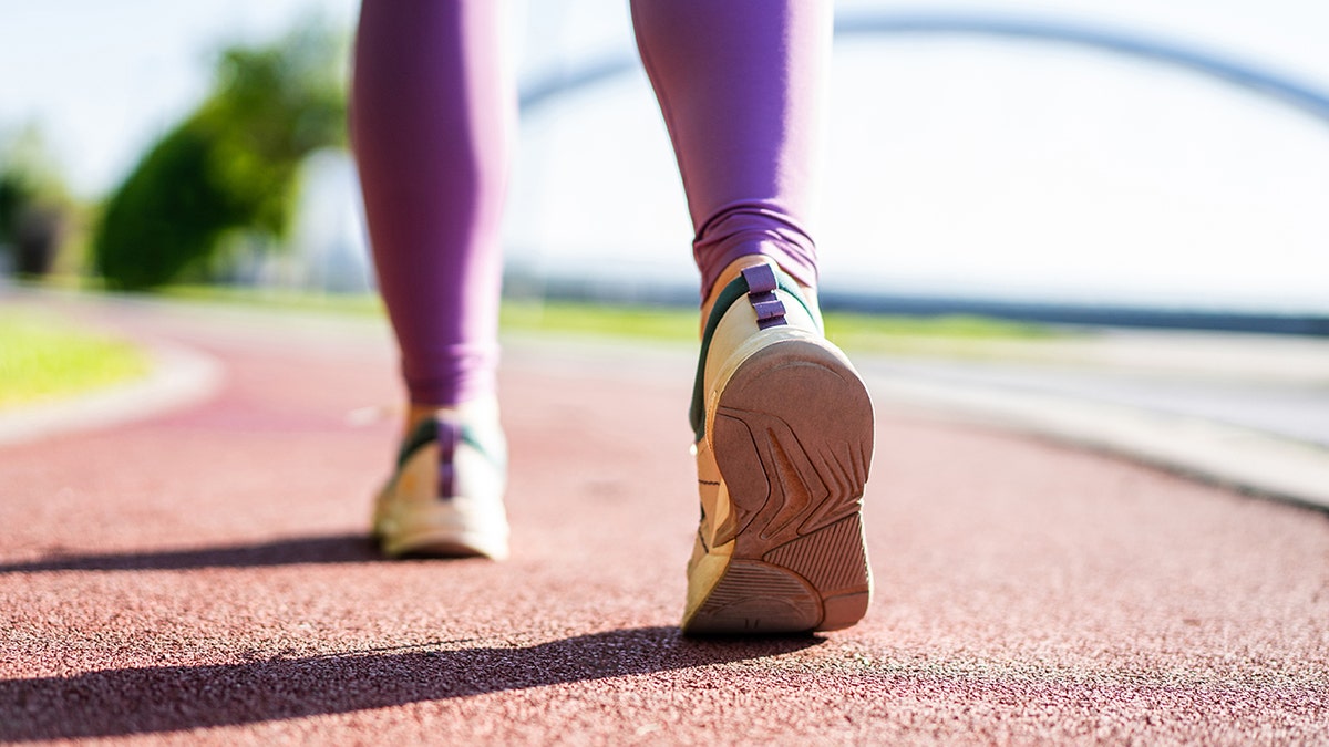 Running shoes of a woman walking on a red track