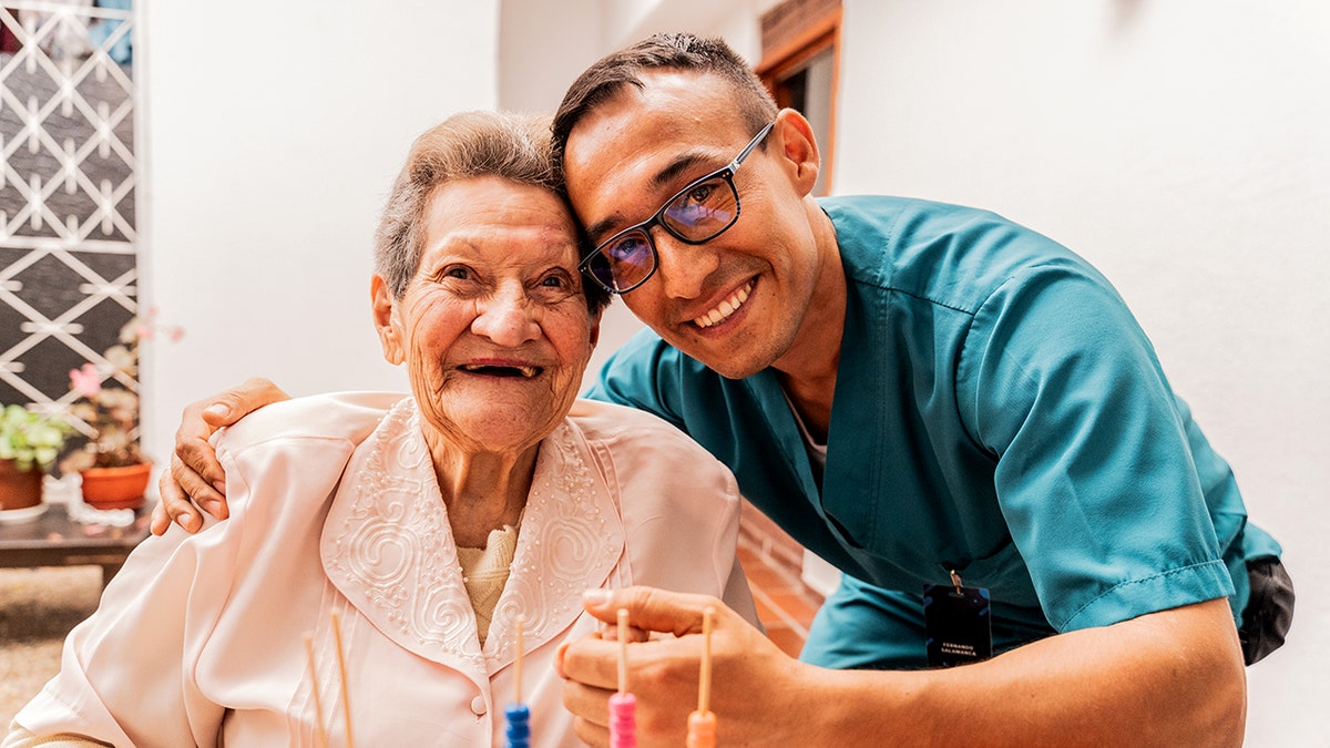Caregiver bending over seated senior woman smiling