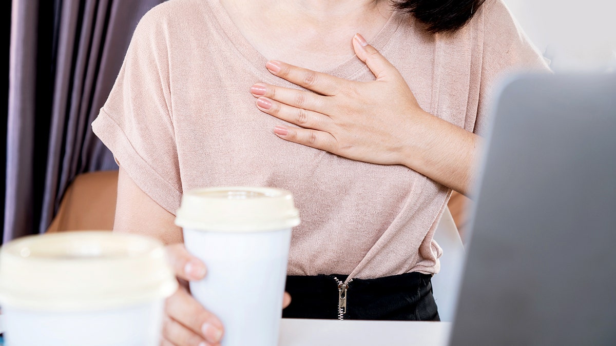 Woman having problems with heart palpitations or heart beating too fast after drinking coffee