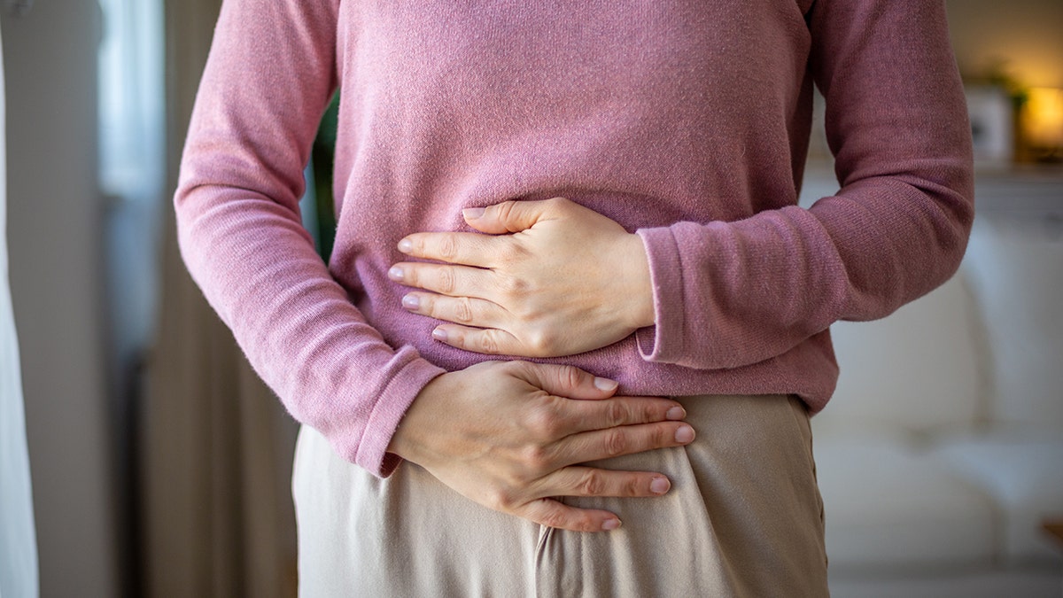Mid adult woman holding her belly suffering from abdominal pain