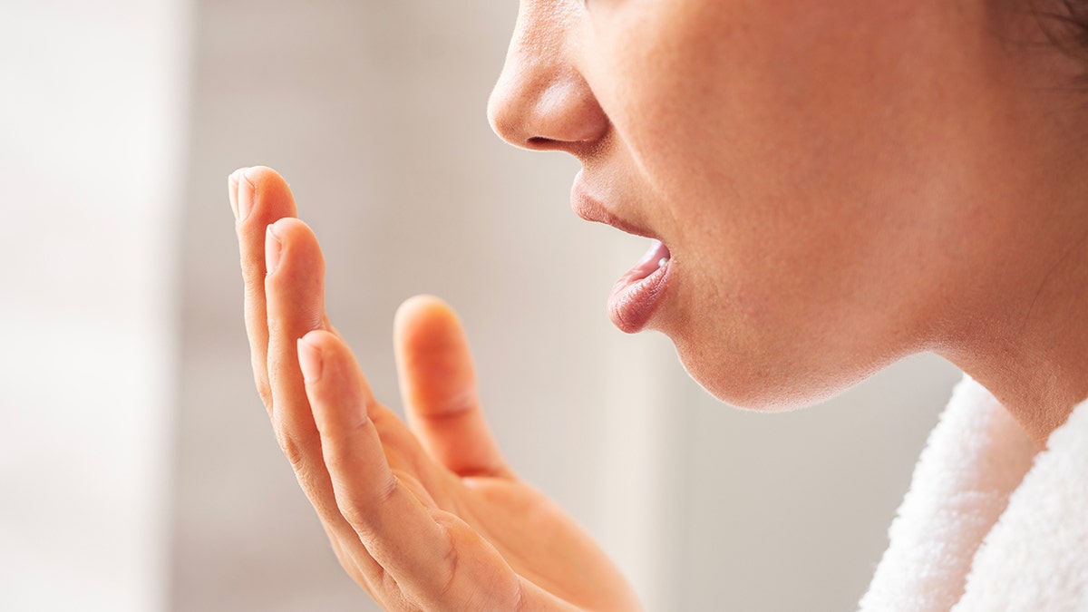 woman checks smell of breath