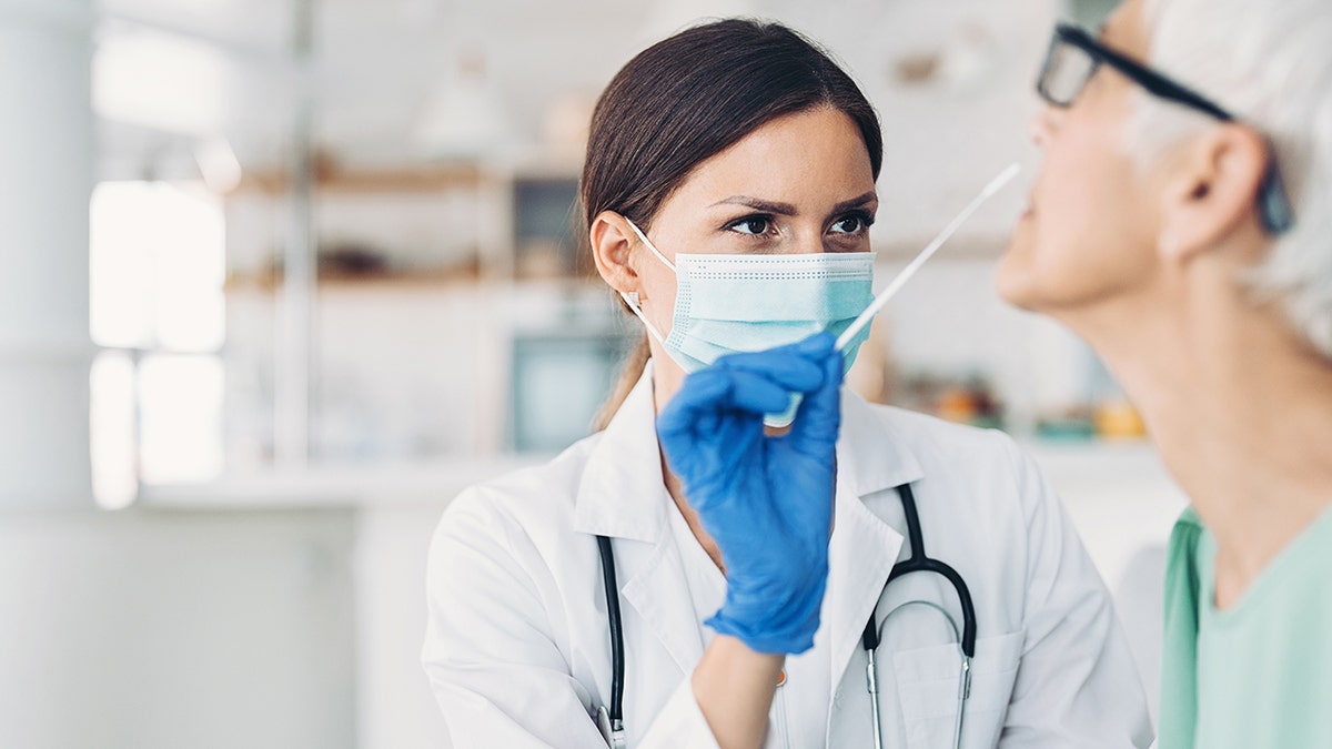 female doctor wearing mask tests patient with nasal swab