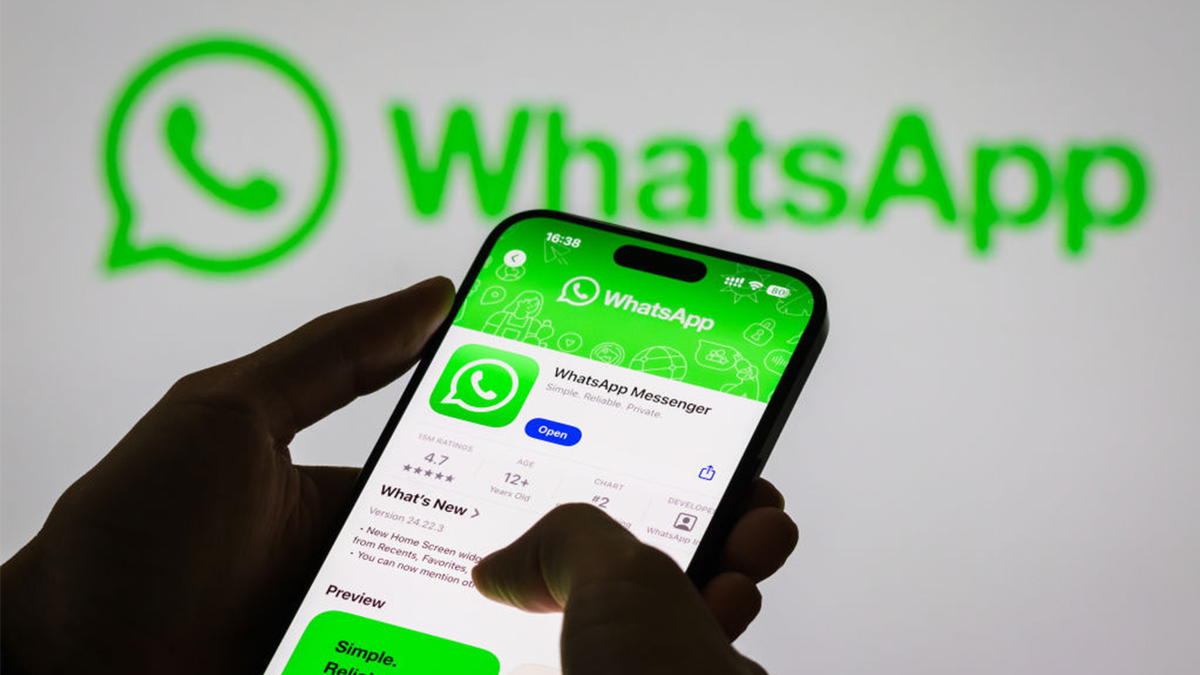 A person holds a smartphone displaying the WhatsApp app