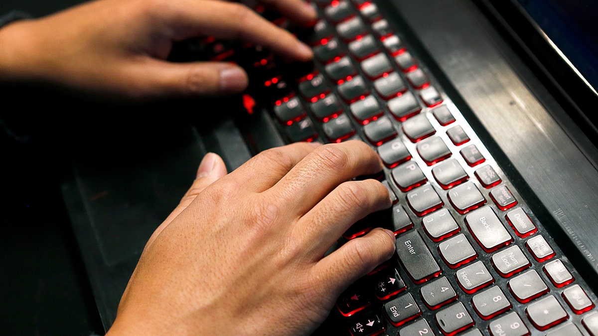 Scammer typing on his laptop.