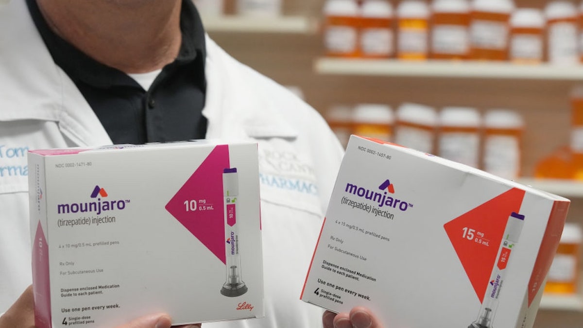 pharmacist holds up two boxes of Mounjaro