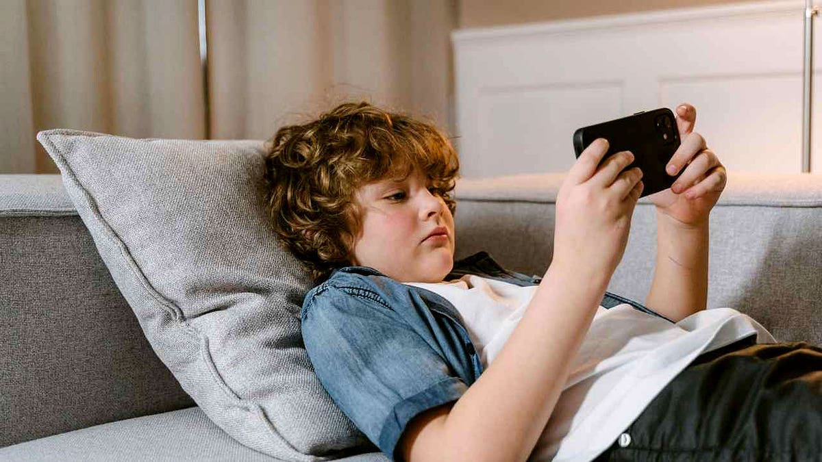 A boy holds a smartphone horizontally.