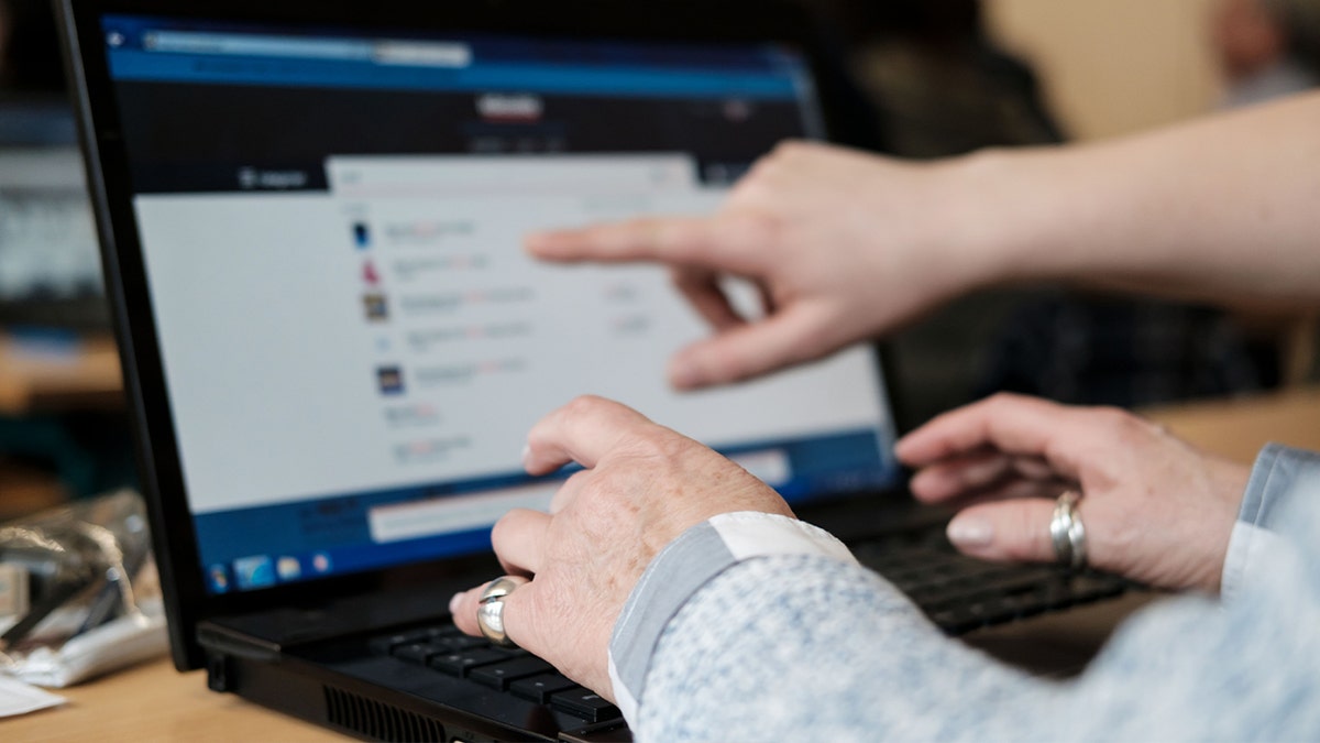 hands of a senior using laptop with person helping