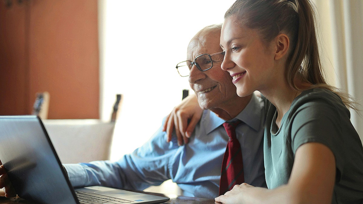 Old man and adult look at a computer